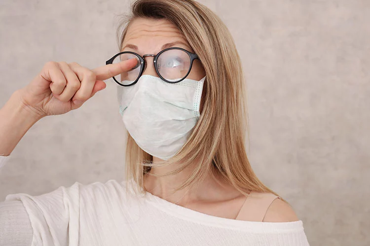 COVID-19 face mask fogging up glasses of young woman wearing them